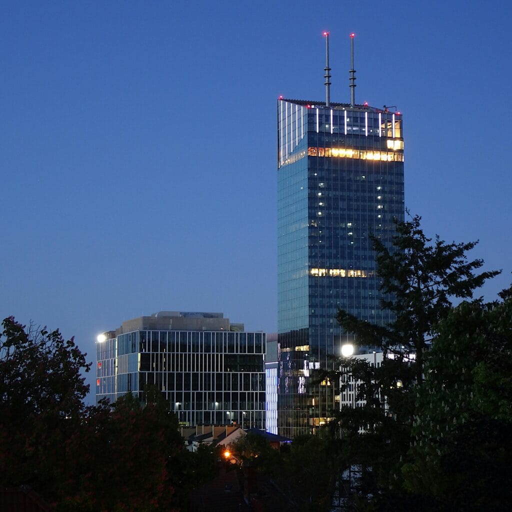 A towering skyscraper in Gdańsk, Poland, lit up against the night sky.