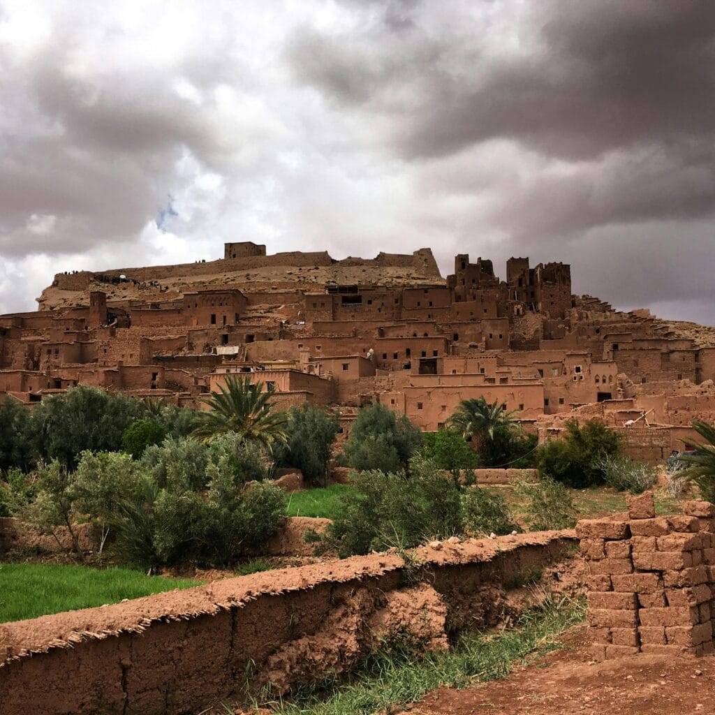 Explore the ancient clay architecture of Aït Ben Haddou under dramatic skies, a UNESCO World Heritage Site.